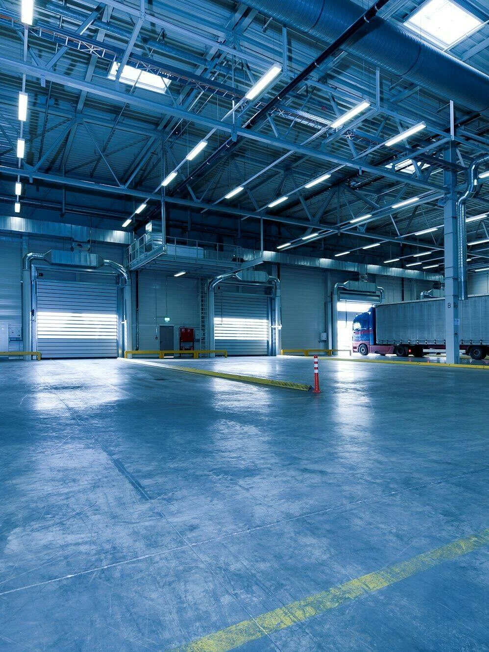 oil-1 Wide view of an empty modern warehouse with industrial lighting and trucks.